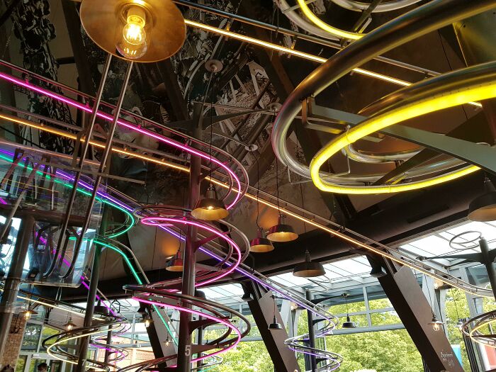 A restaurant interior with a ceiling covered in elaborate, brightly lit metal spirals, showcasing genius ideas for businesses.