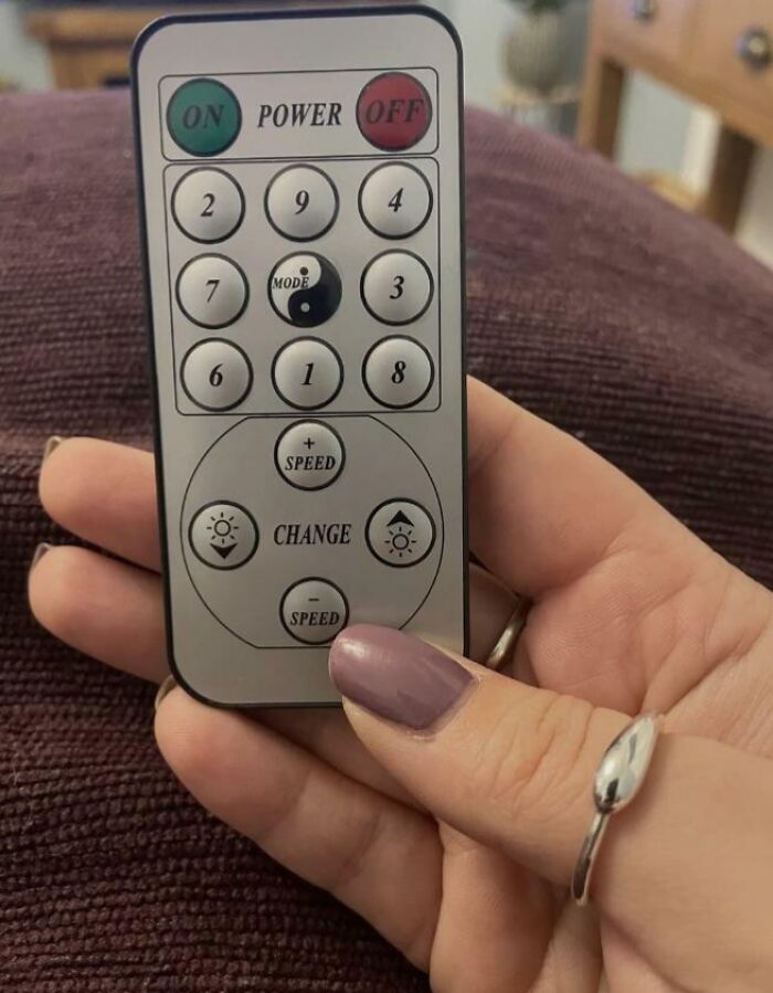 A hand holding a remote control with a confusing layout, an awful design fail.
