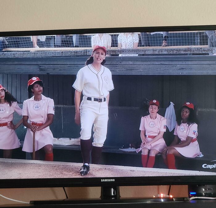Women in vintage baseball uniforms, from a movie scene, on screen as one of the commercials.