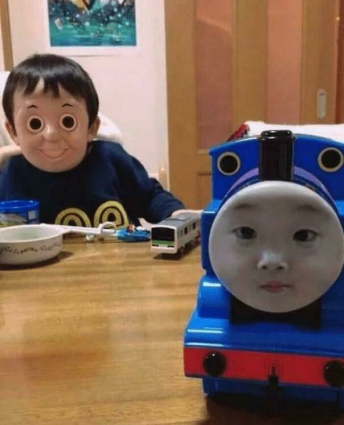 A blursed meme featuring a child with a Thomas the Tank Engine face and a Thomas the Tank Engine toy with a child's face.