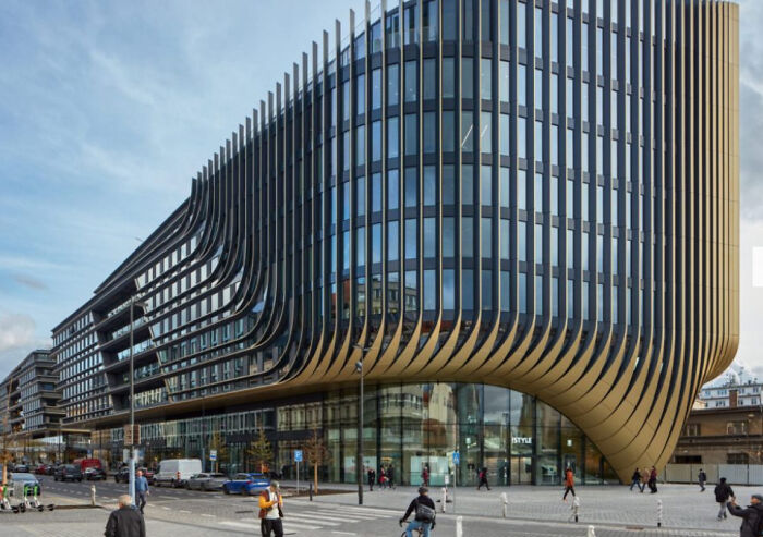 Large, curvilinear modern architecture design building with horizontal wooden fins and ample glass windows.