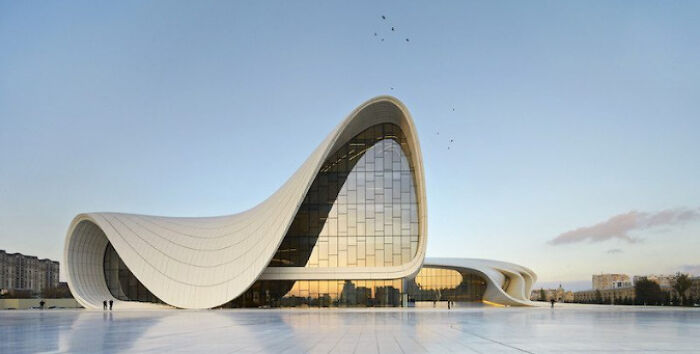 Stunning white, fluid modern architecture design building with large glass windows under a vast sky.