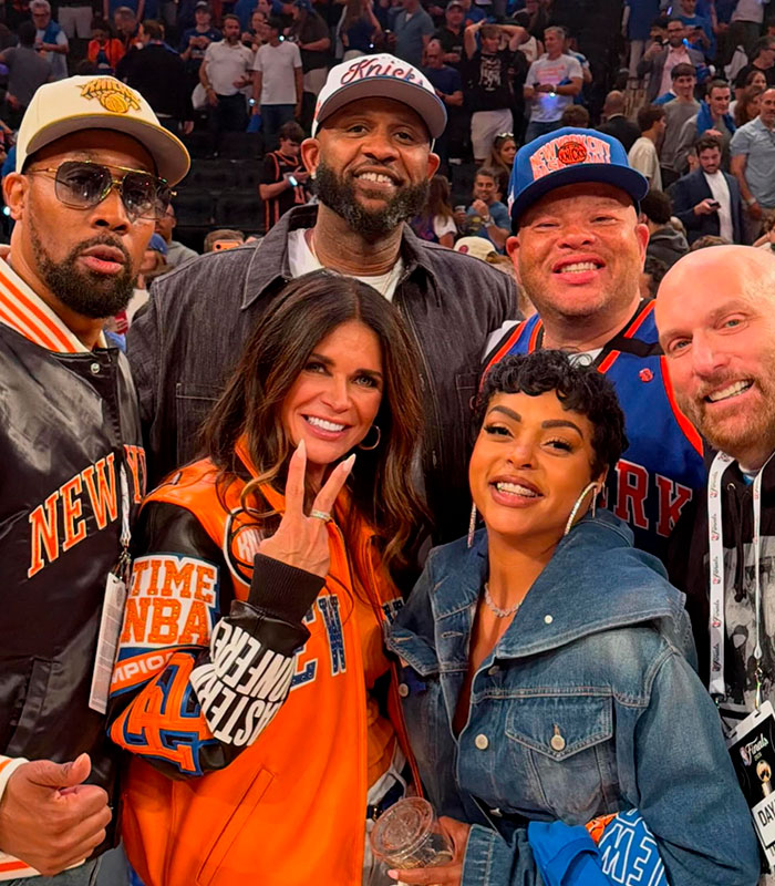 Taraji P. Henson smiling with a group, wearing a denim jacket, at an event, appearance visible.