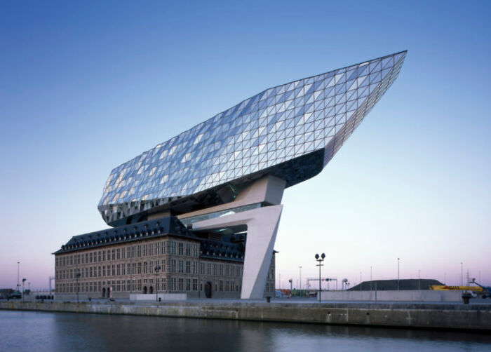 Striking modern architecture design atop a historic building, overlooking water at dusk.