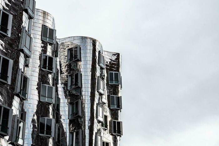 Curved, metallic modern architecture design reflecting light under a bright sky.