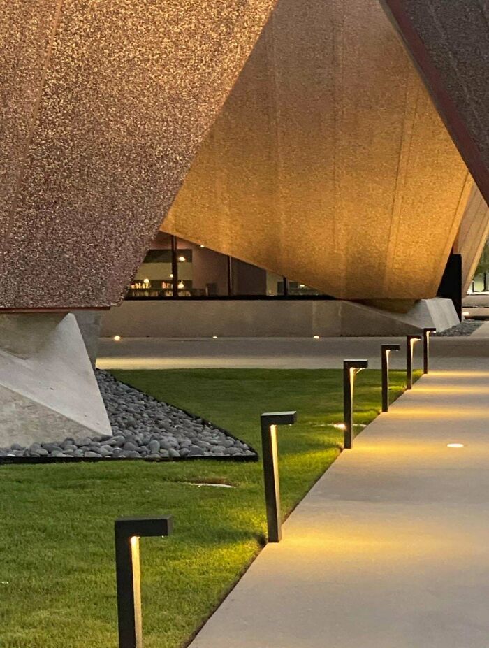 Modern architecture design: Modern outdoor lighting illuminating a walkway beside an abstract building.