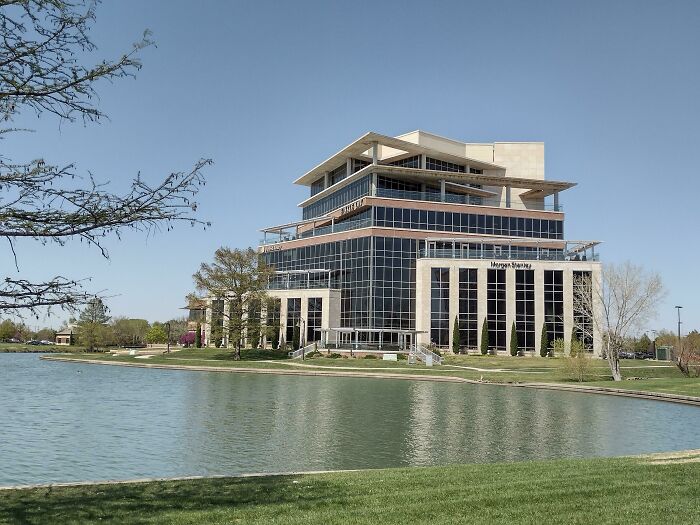 A beautiful modern architecture design building with reflective windows, situated by a tranquil lake.