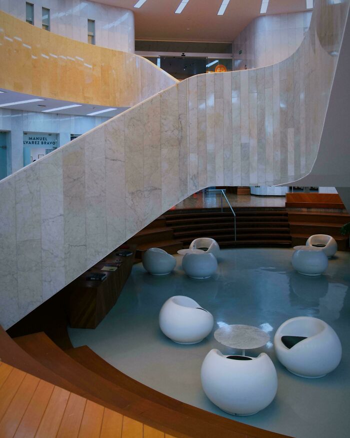 Elegant modern architecture design showcasing a grand, curved marble staircase ascending from a lounge area with contemporary white seating.