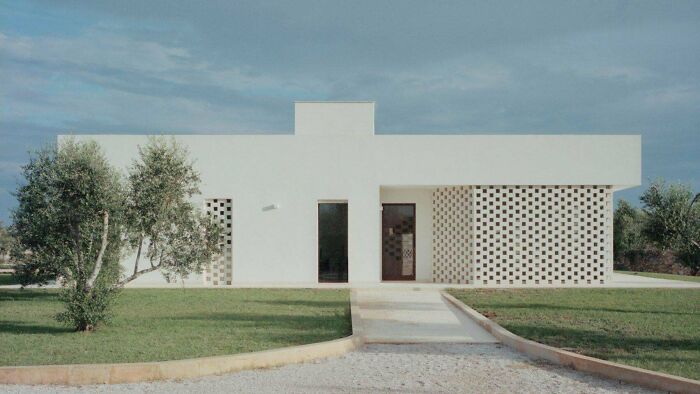 Amazing and beautiful modern architecture designs display a minimalist white house with dark window frames and a perforated brick wall.