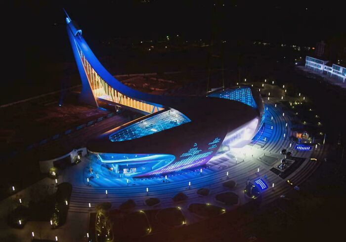 Amazing modern architecture design of a futuristic building with dynamic blue and orange lighting at night.