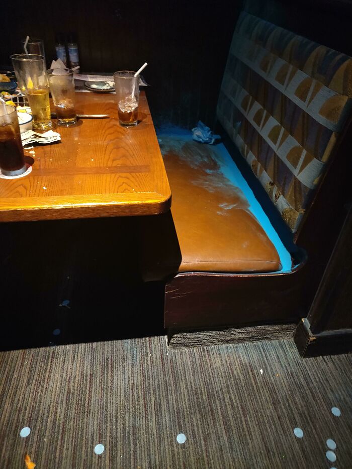 A messy restaurant booth with blue powder on the seat, likely from a gender reveal gone wrong.