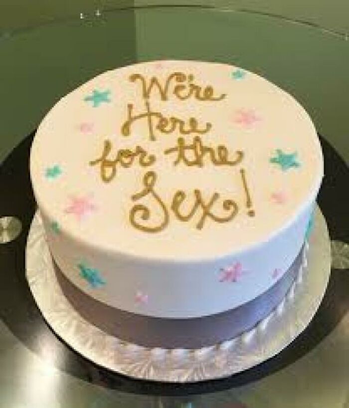 A white gender reveal cake with pink and blue stars, and gold lettering that says 'We're Here for the S*x!'