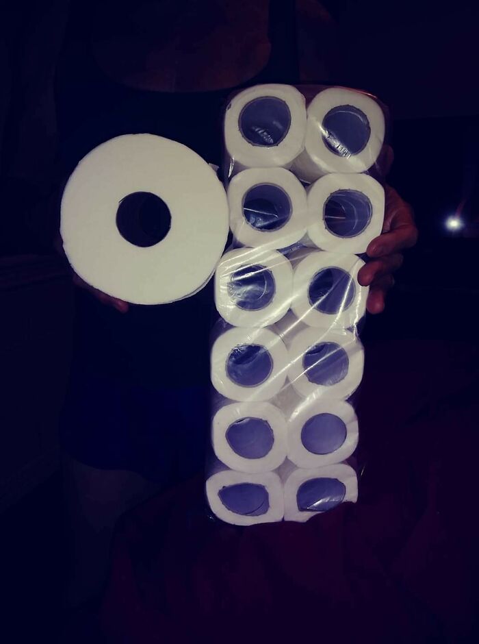 A person holding a large single toilet paper roll next to a small multi-pack, illustrating infuriating marketing practices.