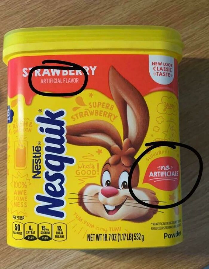 A close-up of a Nesquik strawberry powder container, circled areas show conflicting claims: 'artificial flavor' and 'no artificials,' infuriating marketing practices.