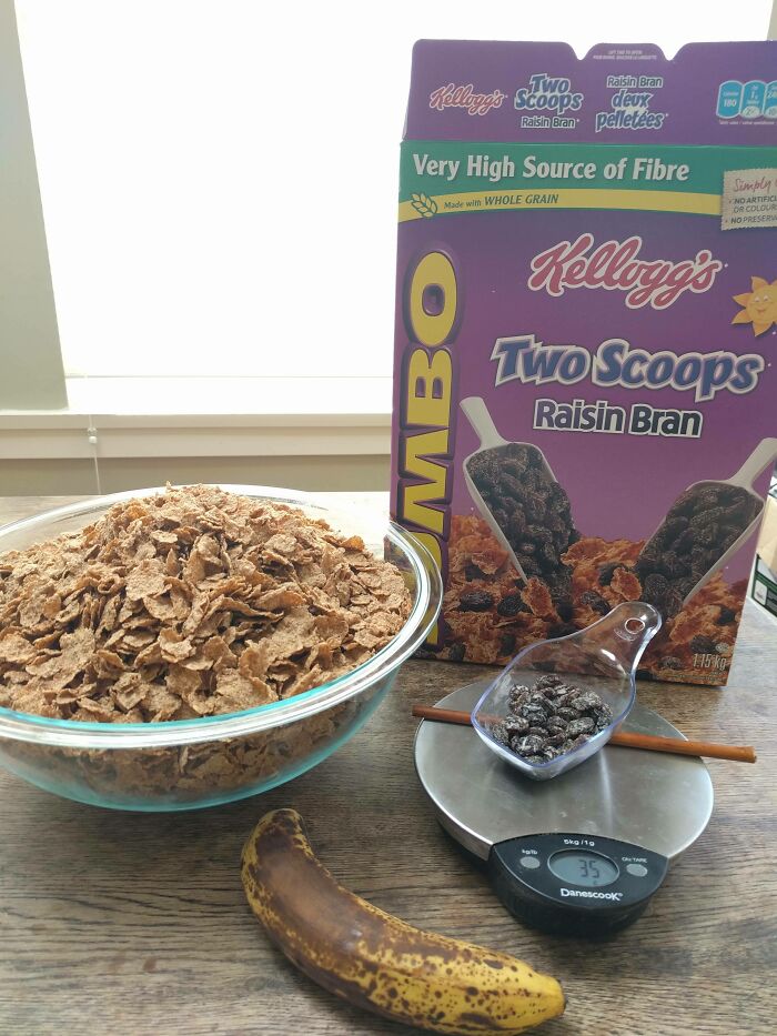 A large bowl of cereal, small amount of raisins, a banana, and a Kellogg's Raisin Bran box, showing infuriating marketing practices.