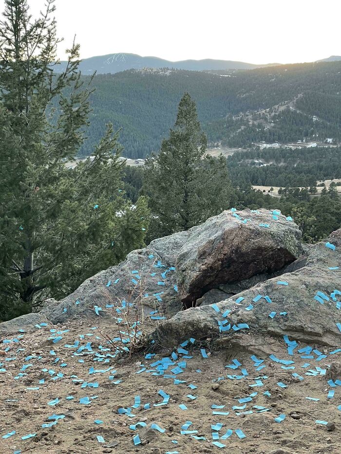 Blue gender reveal confetti littering a rocky mountaintop, highlighting an irresponsible gender reveal.