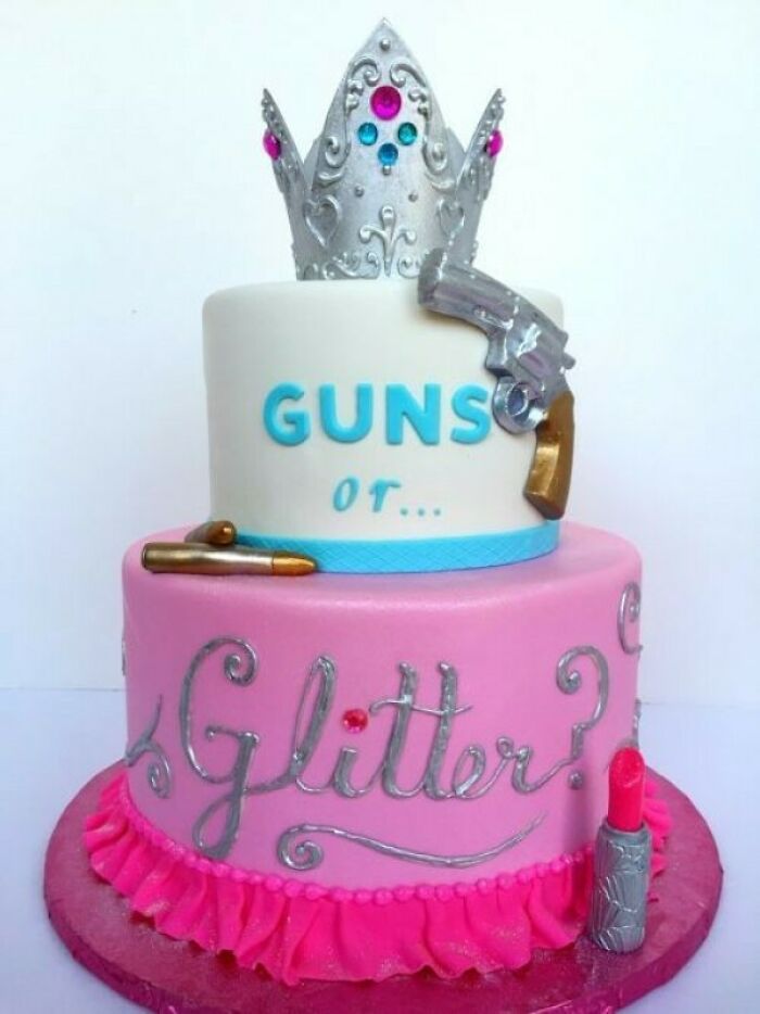 A two-tier gender reveal cake with a silver crown, a gun, and the words Guns or Glitter? on it.