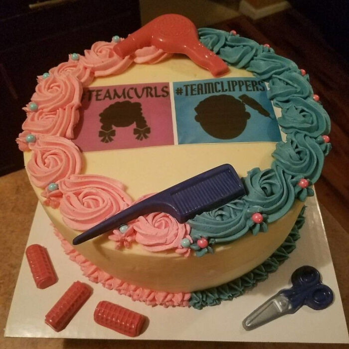 A gender reveal cake decorated with pink and blue frosting, featuring Team Curls and #TeamClippers signs.