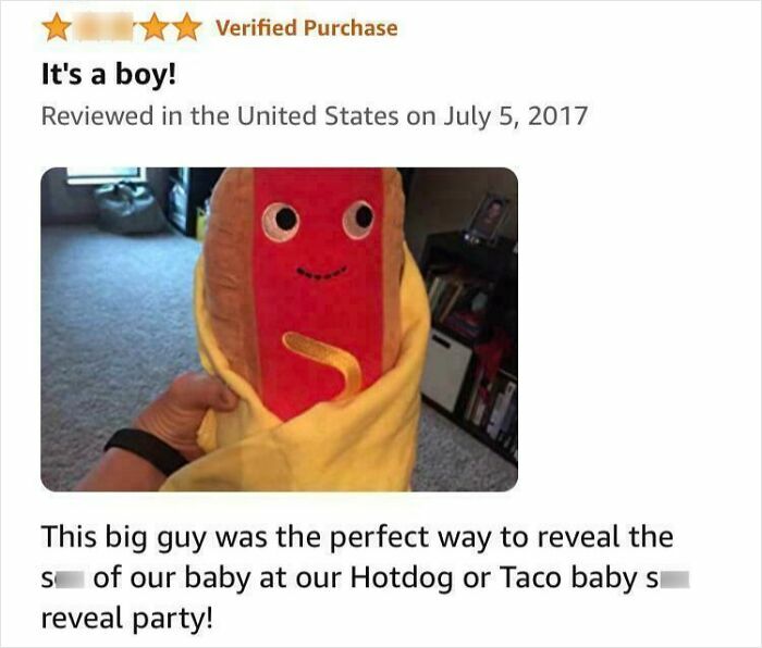 A plush hotdog in a yellow blanket used for a gender reveal party, with text saying It's a boy!