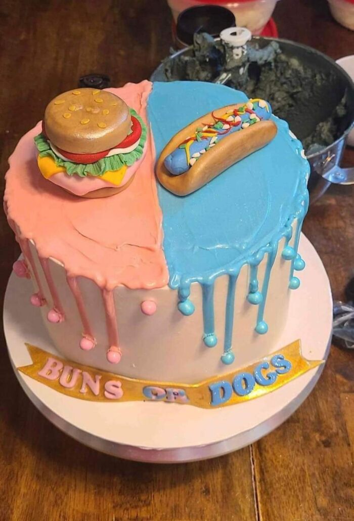 A split Gender Reveal cake, half pink with a burger and half blue with a hot dog. Some parents are judged for this.