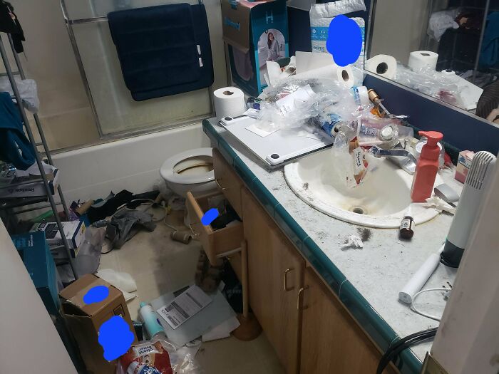 A extremely messy bathroom with a toilet, sink, and bathtub, covered in trash and items. Men freak out.