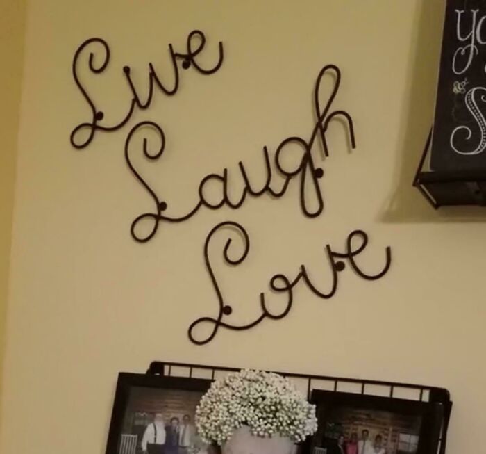 A wall decor that says Live, Laugh, Love, with family photos below, showcasing men freaked out by home aesthetics.