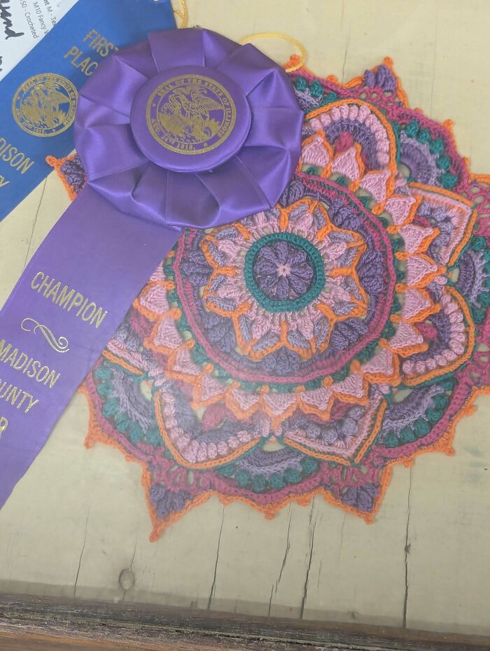 Intricate crochet mandala with award ribbons representing creative crochet project