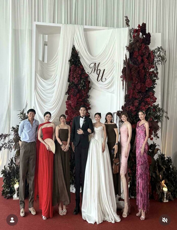 A group of people, including a bride and groom, who didn't try to look natural on social media, posing at a wedding.