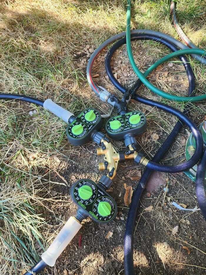 Clever solution: multiple hoses and timers connected for an intricate watering system, repurposing random junk for efficiency.