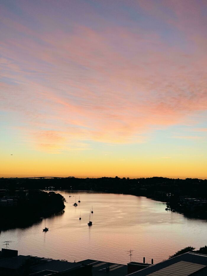 A beautiful Australian sunset over a river with several boats, reflecting the colorful sky. Aussie scenic understanding.