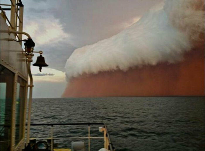A massive dust storm rolling over the ocean, viewed from a boat, makes one question if these real photos were edited.