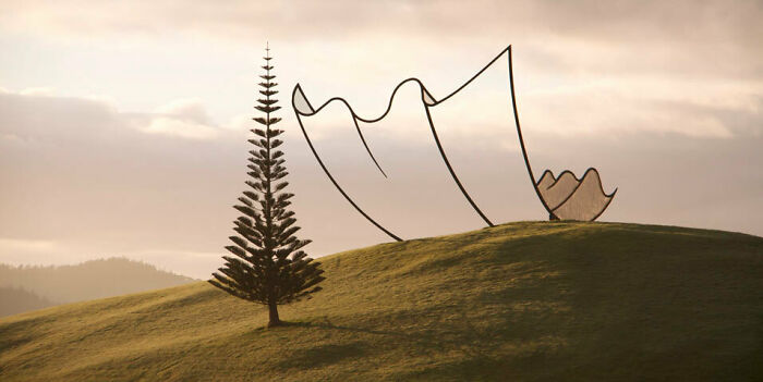 Real photos of a tall, thin tree next to a large, abstract metal sculpture on a grassy hill, making you question if edited.