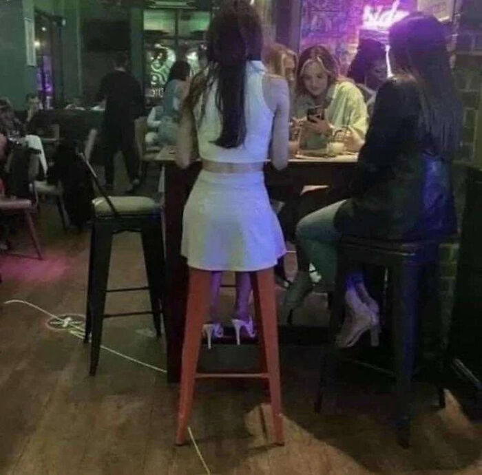 A woman sitting on a high stool in a bar, a real photo that makes your brain question reality.
