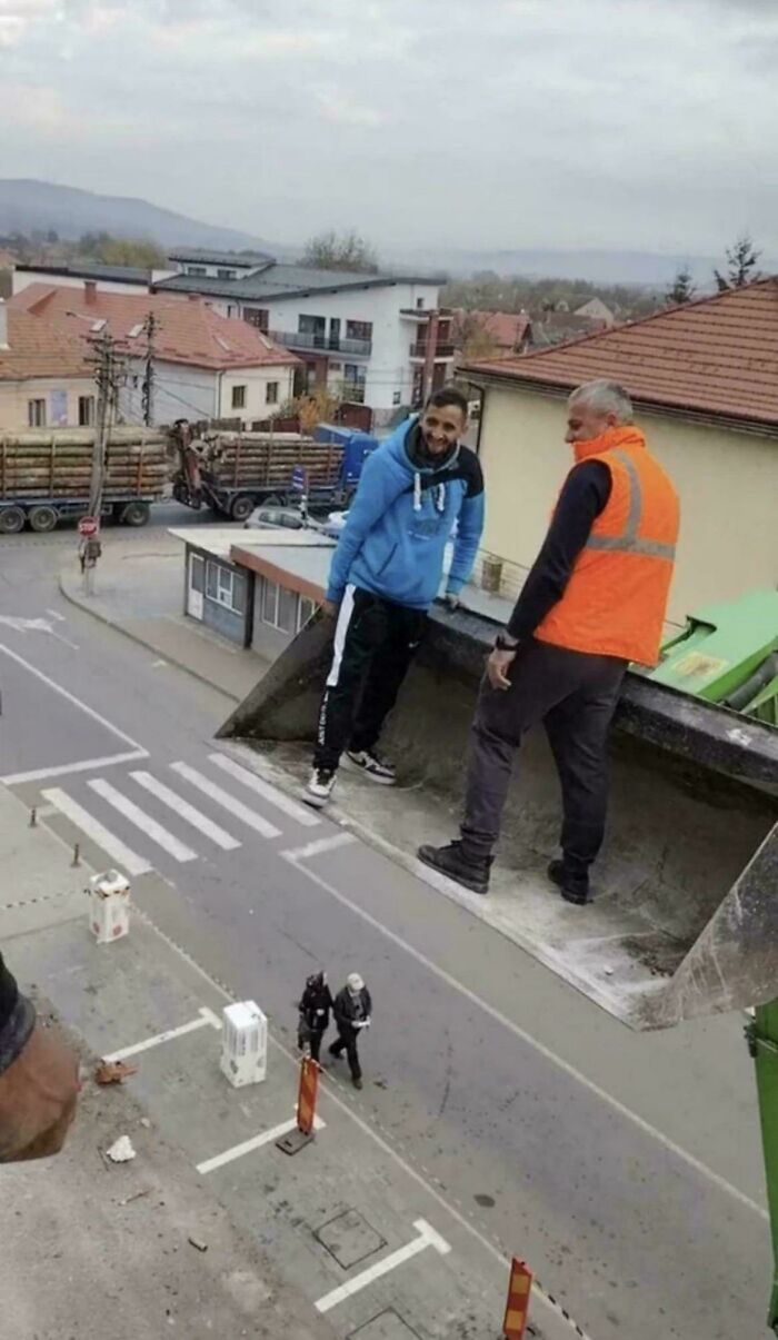 Two men appearing to stand on a tilted section of road or building, an optical illusion caused by perspective. Real photos that make your brain question if they were edited.