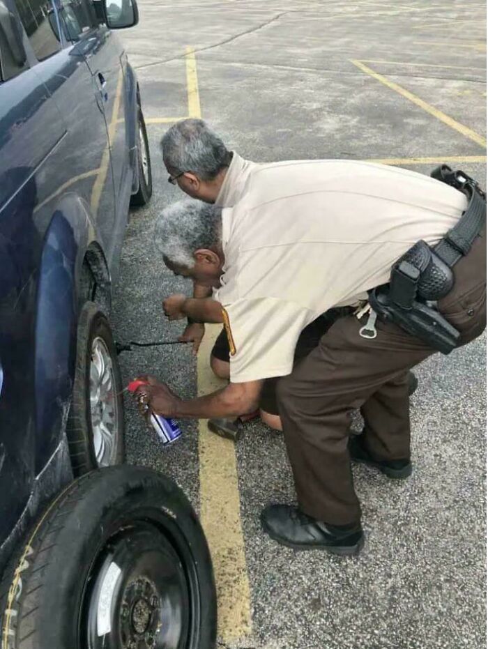Two men, one seemingly kneeling inside the other, changing a tire on a car. This perspective creates an unusual optical illusion. Real photos that make your brain question if they were edited.