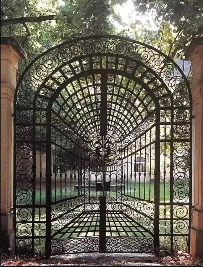 An ornate, arched wrought-iron gate with a clever design that creates a striking visual depth. Real photos that make your brain question if they were edited.