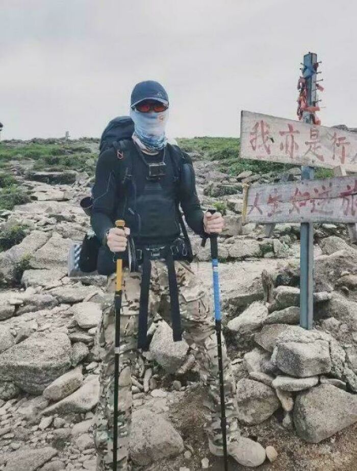 A person in camouflage holding trekking poles on a rocky terrain, an optical illusion making it seem they have no lower body. Real photos that make your brain question if they were edited.