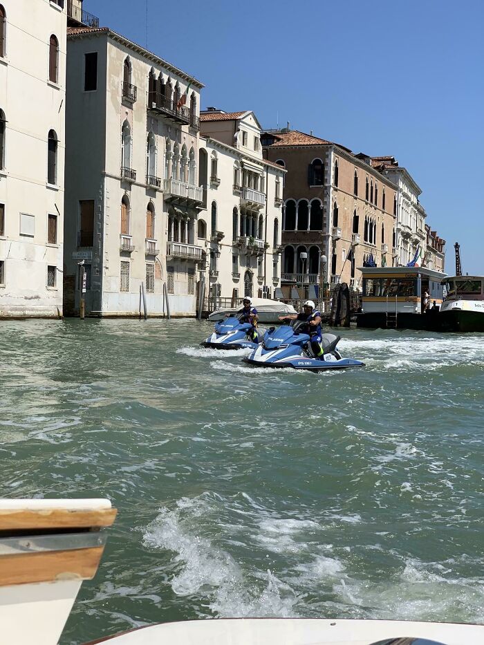 Two jet skis on a Venice canal, featuring real photos that make your brain question if they were edited.