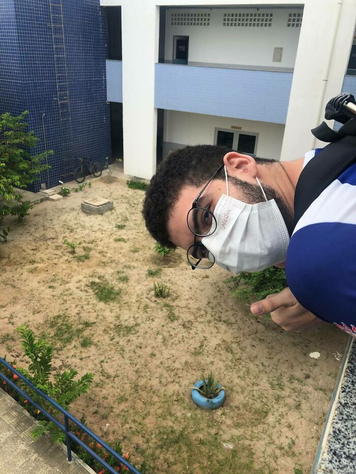 A man wearing a face mask and glasses looks down over a ledge, making the brain question if the photo was edited.