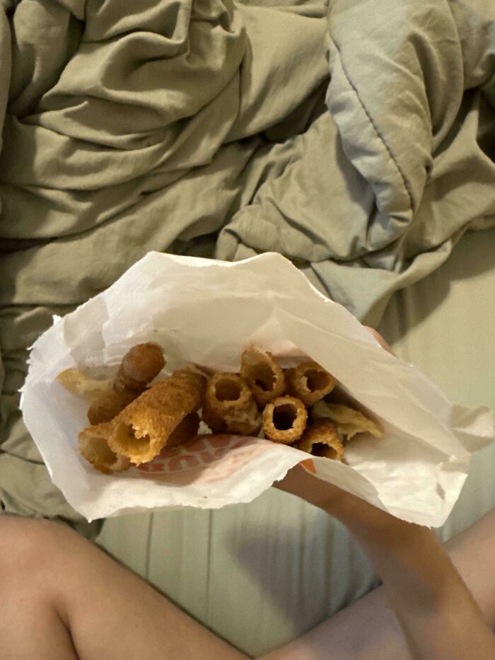 A person holding a bag of discarded fried food on their lap, forgetting something important.