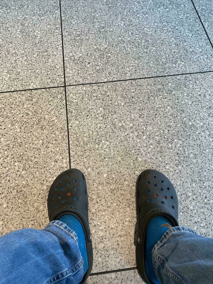 A person wearing Crocs with blue socks, showing a moment of forgetting something important for their day.