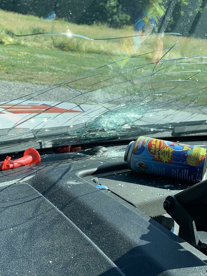 A cracked car windshield with a can on the dashboard, a day ruined by forgetting something important.
