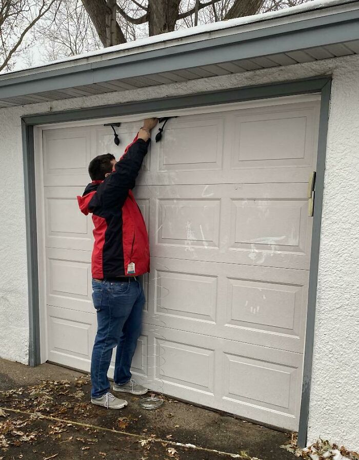A person trying to open a garage door from the outside, an instance of forgetting something and ruining the day.