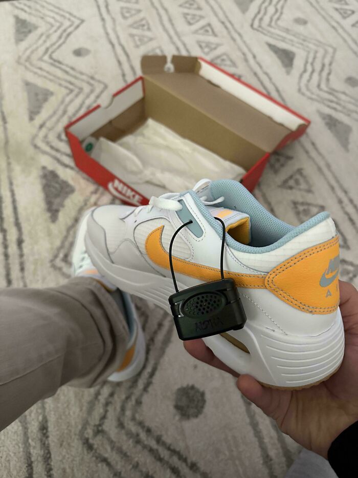 Person forgetting to remove a security tag from new Nike shoes, ruining their day.