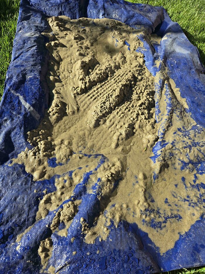 A blue tarp covered in a large amount of wet, sandy mud, possibly a consequence of forgetting something important.