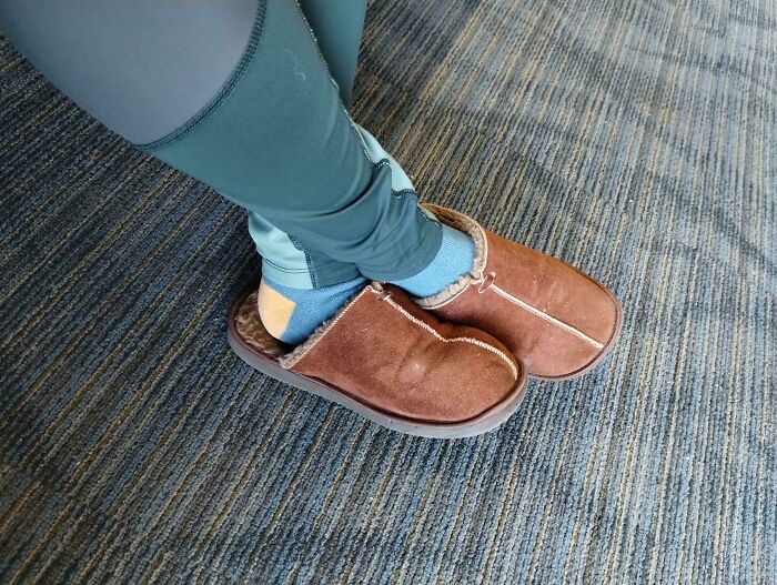 Someone wearing fuzzy slippers with blue socks, forgetting proper shoes, ruining their day.