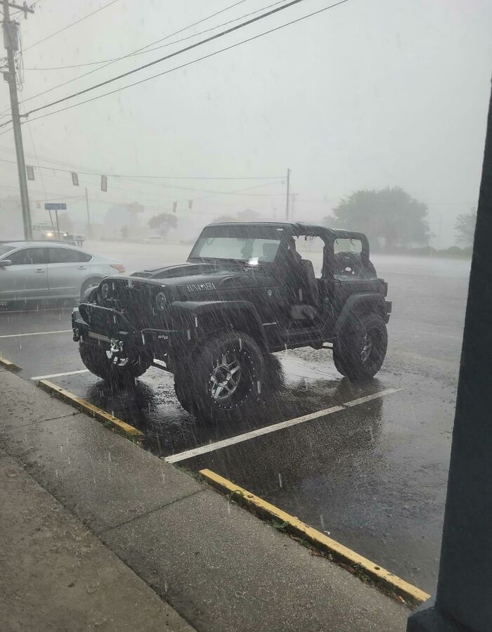 A black Jeep parked in heavy rain, demonstrating how forgetting something important can ruin your day.