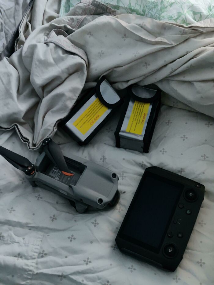 A drone with two detached batteries on a bed, a situation that could ruin an entire day by forgetting something.