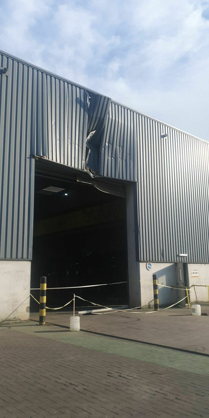 A metal building with a large section of its wall severely dented and crumpled, an important repair needed.