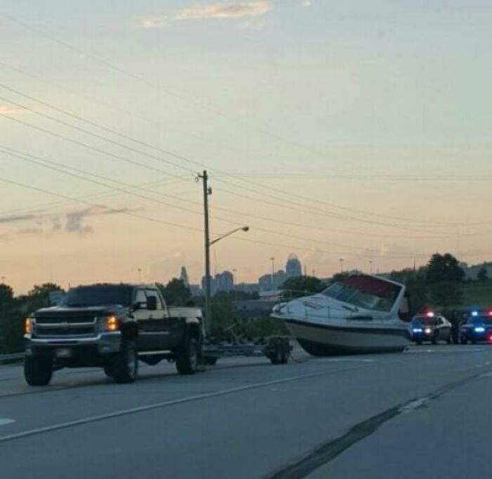 A boat detached from its trailer on the side of a road, an important thing forgotten.
